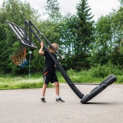 Person flyttar Court Champ portabel basketkorg på transporthjulen