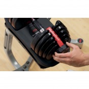 Detaljbild på justerbar hantel där en hand vrider viktvredet på svart viktsegment.