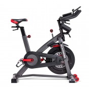 Schwinn IC8 spinningcykel med svart stålram, synligt svänghjul framtill och röda justeringsdetaljer.