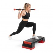 Kvinna gör utfall med Aerobic Bar på axlarna och stepbräda