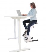 Här visas en person som använder en motionscykel, placerad vid ett justerbart höjdbord. Denna bild illustrerar hur man kan integ