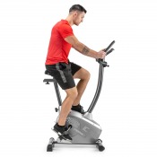 Motionscykel Gymstick IC3.0 med person som cyklar, sedd från sidan i inomhusmiljö