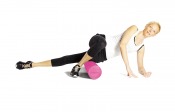 Foamroller i ljusrosa utförande använd under benet i träningsmiljö.