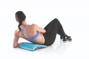 Kvinna lägger sig bakåt över Gymstick Active Back Stretcher för att stretcha ryggen