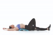 Kvinna ligger på rygg med Gymstick Active Back Stretcher under ländryggen
