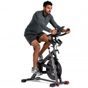 Schwinn IC8 spinningcykel använd av person i framåtlutad position mot styret i ljus studiomiljö.