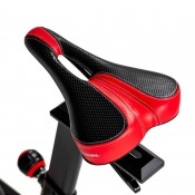 Detaljbild på vadderad sadel i svart med röda detaljer, monterad på justerbar sadelstolpe.