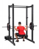 Power rack med skivstång och person som tränar inne i racket, i gymmiljö.