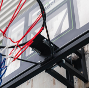 Detaljbild på röd basketkorg med vitt nät och svart fäste, sedd underifrån.