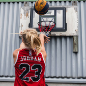 Court Layup Hoop monterad på vägg med person som gör layup med boll, fotograferad utomhus.
