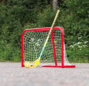 Court Mini Goal i rött med nät uppställt utomhus på grus med grönska i bakgrunden.