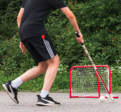 Court Mini Goal i rött med nät på grus med person som skjuter en fotboll, i utomhusmiljö.