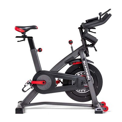 Schwinn IC8 spinningcykel med svart stålram, synligt svänghjul framtill och röda justeringsdetaljer.