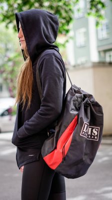 Svart ryggsäck med röd detalj, buren på ryggen av en person utomhus.